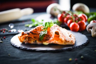 Lezzetli İtalyan calzone pizza yemeği ve taze malzemeler.