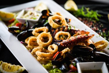 Ahtapot, karides, karides, karides, kabuk, mürekkep balığı ve limon soslu taze balık karışımı lezzetli bir deniz ürünleri tabağı.