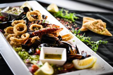 Ahtapot, karides, karides, karides, kabuk, mürekkep balığı ve limon soslu taze balık karışımı lezzetli bir deniz ürünleri tabağı.