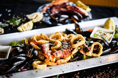 Ahtapot, karides, karides, karides, kabuk, mürekkep balığı ve limon soslu taze balık karışımı lezzetli bir deniz ürünleri tabağı.