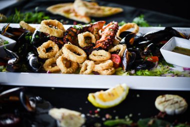 Ahtapot, karides, karides, karides, kabuk, mürekkep balığı ve limon soslu taze balık karışımı lezzetli bir deniz ürünleri tabağı.