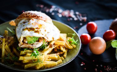 Lezzetli ev yapımı tavuk burgeri patates kızartması ve kızarmış yumurta.