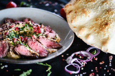 Kızarmış biftek ve nar tohumlu Lübnan humus yemeği.