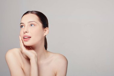 Temiz, taze tenli ve koyu renkli genç bir kadın kendi yüzüne dokunuyor. Çıplak makyaj malzemesi. Güzel kız yüz bakımı.