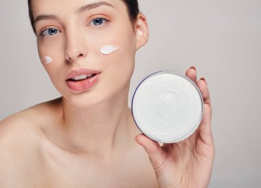 Temiz tenli ve elinde şişe tutan mavi gözlü güzel bir genç kadın. Güzellik yüz bakımı. Yüz bakımı. Kozmetoloji.