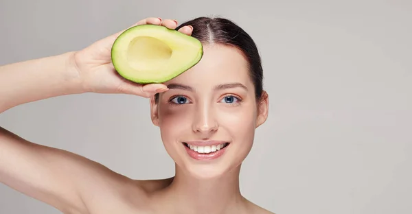 Cheerful and happy brown-haired nude lady with perfect pure shine skin beautiful smile and avocado on top in hand near the forehead — Stock Photo, Image
