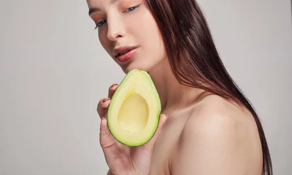 Dame mit braunem Hören mit perfektem reinem Glanz Haut mit Avocado in der Hand — Stockfoto