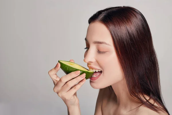 Profile side photo portrait of attractive tender brown-haired lady with perfect pure shine skin eating avocado — Stock Photo, Image