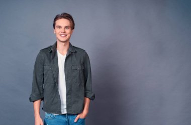 Neşeli, genç ve yakışıklı bir adam, rahat bir poz vermiş, elleri ceplerinde, gülümsüyor, alışveriş merkezinde alışveriş yapan sıradan bir adam, hediyeler alıyor. Erkek kamera meraklısı gibi görünüyor. Boşluğu kopyala.