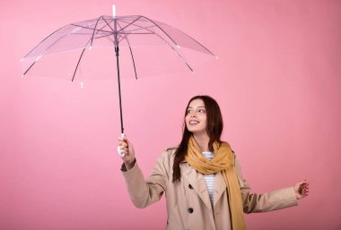 Zarif, beyaz bir bayan, yağmurlu sonbahar havasında seviniyor, şeffaf bir şemsiyenin altında saklanıyor. Romantik bir havanın tadını çıkarıyorum. Uzayı kopyala Mevsim için hava tahmini.