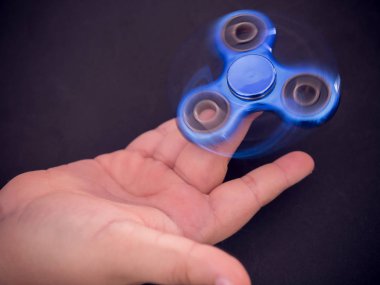 Koyu arkaplanda bir çocuk elinde mavi hareketli dönen.