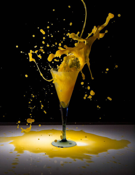 Drink cocktail peach juice splash of glass with frozen drops on a black background.