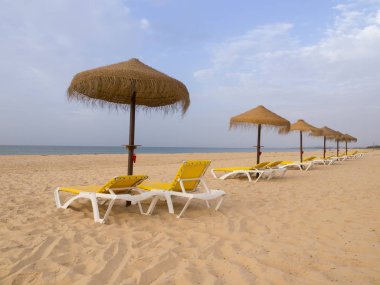 Güneş yatakları ve saman şemsiyeli plaj sahnesi. Yaz tatili konsepti