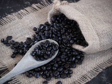 Kahve çekirdekleri torbanın içinden taştan bir masa ve tahta kaşık çıkıyor.