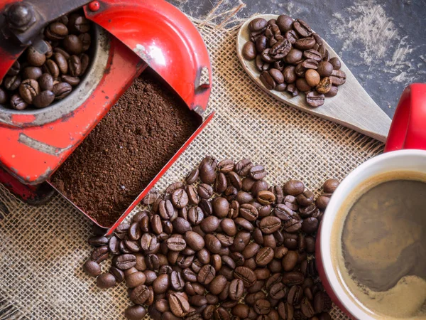 Szene über Kaffee von oben. Vintage rote Kaffeemühle, rote Tasse, Holzlöffel und Kaffeebohnen — Stockfoto