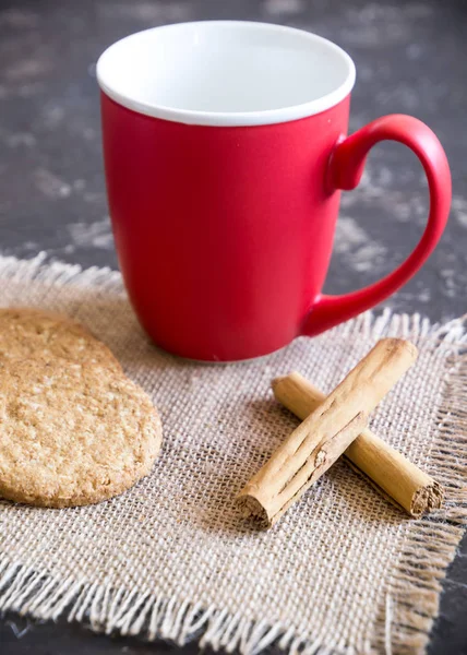 Kırmızı kahve fincanı, tarçın çubuğu ve kekler.