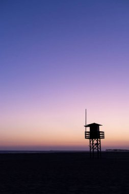 Gün batımında Isla Canela sahilindeki cankurtaran evinin silueti. Huelva, Endülüs, İspanya.