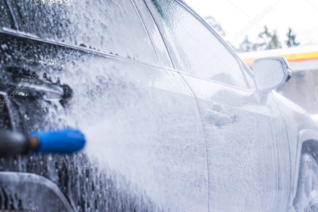 Close-up of the car's headlight, foam on the car at the car wash