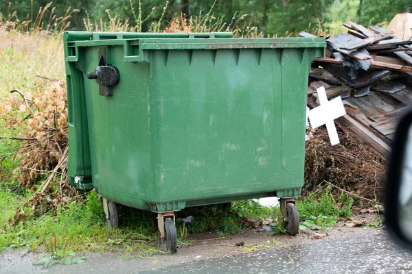 green trash cans near houses among trees