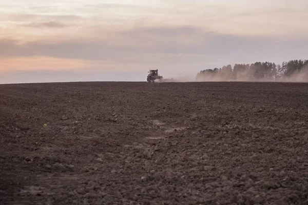 Een Trekker Een Veld Ploegt Grond Oprijzend Stof Bij Zonsondergang — Stockfoto