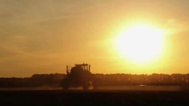 夕暮れ時のフィールドに化学物質を散布トラクターです トウモロコシの日の夕暮れ時 フィールドにおける施肥 — ストック動画