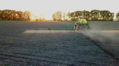 Bir dron püskürtme bir alanda gün batımında çekim. Çiftlikte alanda çalışma traktör püskürtücü üstten görünüm. 