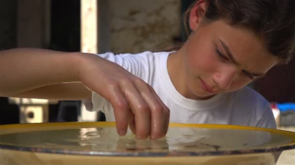 少年十代の水スローモーションで洗面器で遊んで 悲しい子がスローモーション撮影 水の表面に沿って指を移動します — ストック動画