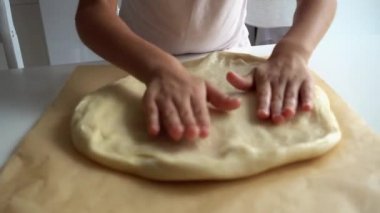 Bebek eller bir pizza hamuru 4k video yakın çekim. Çocuk elleri ile pişirme için gözleme hamur rulo. 