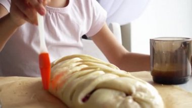 Kız bir çırpılmış yumurta ile kirazlı turta yağlar. Çocuk yumurta, yağlar pişirme için hamur. 