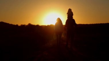 Alanında genç aile gün batımında. Baba Anne ve kızı günbatımında evinin önünde oynarken. Üç kişilik bir aile bkz: çıkış yapan güneş. 