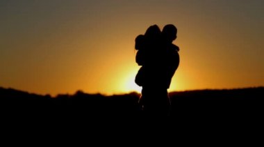 Baba ve kızı günbatımında oynamak. Baba hugs ve onun kızı günbatımında atar. 