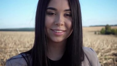 Genç ve güzel bir kız kameraya gülüyor ve lensi eliyle kapatıyor. Doğada bir kadın portresi, kamera önünde poz veriyor..