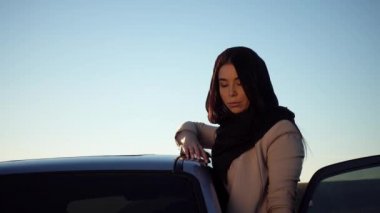 Arap kız arabasını mahalleden inceliyor. Arabanın yanında genç bir Müslüman kadın portresi. 