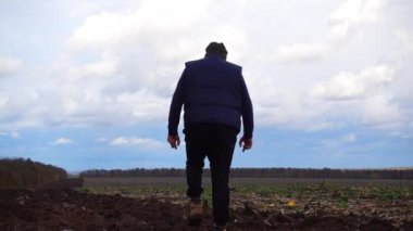 Bir çiftçi bir tarlayı traktör görünüyor. Bir adam onun tarlayı denetler.  