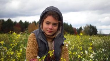 Sonbaharda çiçekli bir alanda bir çocuk portresi. Sonbaharda bir paradoksal çiçekli alanının arka plan üstünde bir oğlan. 