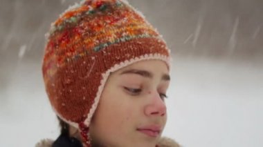 Çocuk yüz portresi kar yağışı kapatın. Çocuk genç düşen kar kış aylarında görünüyor.. 