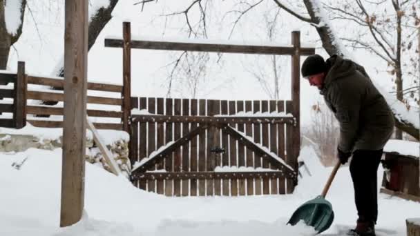 若い男は 彼の庭に雪の中をクリーンアップします 髭の男彼の家の近くの雪をクリーンアップします — ストック動画