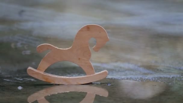 雨の中で水たまりに木製のおもちゃの馬 子供の頃公園に残された子供のおもちゃの馬 — ストック動画