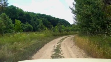 Araba penceresinden bir ülke yol görünümünde sürüş. Arabadan kırsal dolambaçlı toprak yol görünümü. 