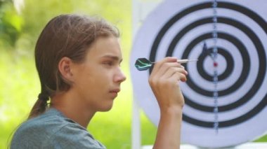 Dart oynayan genç bir çocuğun portresi. Bir çocuk açık dart oyunu oynar. 