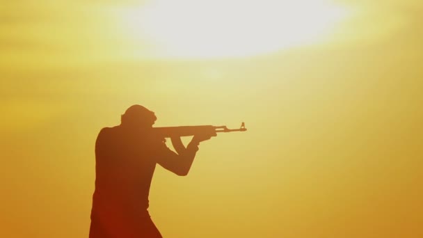 日没の日にカラシニコフとイスラム戦士 イスラム教徒の戦闘機は日没時に機関銃で訓練している — ストック動画