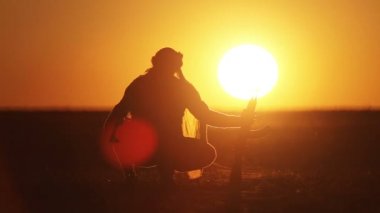 Günbatımında Kalaşnikof ile İslam savaşçısı. Müslüman savaşçı gün batımında makineli tüfekle antrenman yapıyor.. 