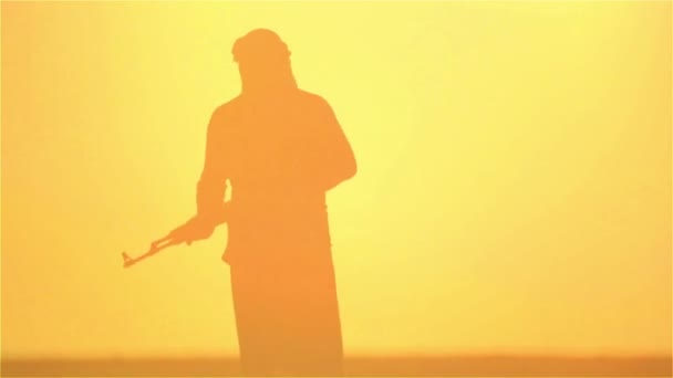 Islamischer Krieger mit Kalaschnikow am Tag des Sonnenuntergangs. Muslimischer Kämpfer trainiert bei Sonnenuntergang mit einem Maschinengewehr. 