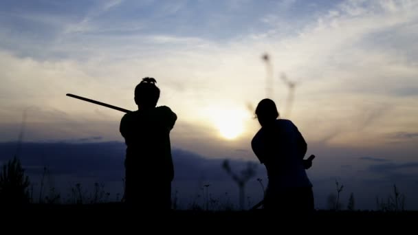 Teenager fechten mit Samurai-Schwertern. Silhouette von trainierenden Kindern auf einem Feld mit Schwertern. 
