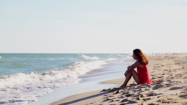 Młoda Dziewczyna Siedzi Sama Wybrzeżu Młoda Kobieta Czerwonej Sukience Siedzi — Wideo stockowe