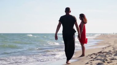 Bir adam ve bir kadın denizin kenarında duruyor. Genç bir çift okyanus boyunca yürüyorlar.. 