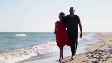 Bir adam ve bir kadın denizin kenarında duruyor. Genç bir çift okyanus boyunca yürüyorlar.. 