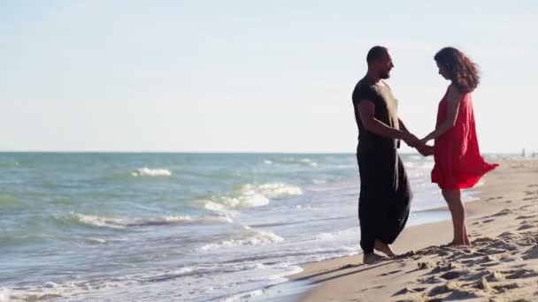 海のそばに男と女が立っている 若い夫婦が海を歩いている — ストック動画