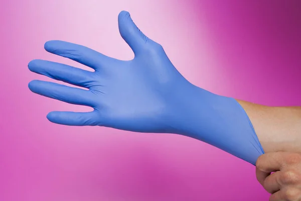 Pink izole mavi bir lateks eldiven giymiş eller