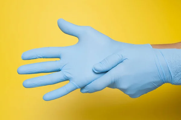 Koruyucu mavi eldiven izole sarı zemin üzerine koyarak doktor